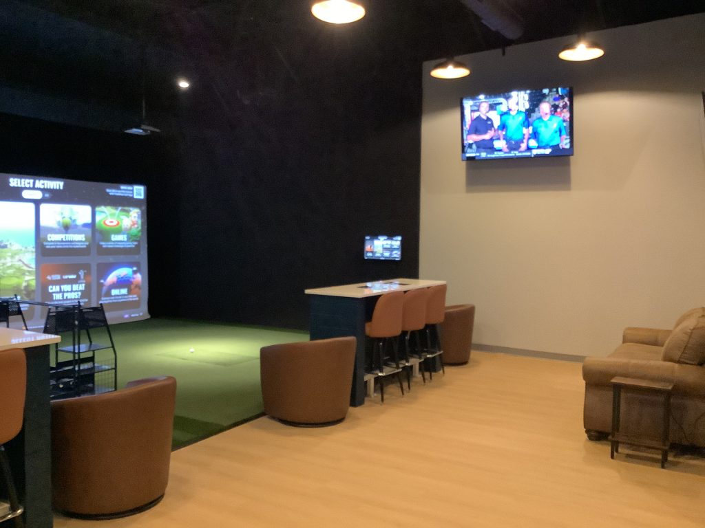 A hitting bay, bartop seating and televisions inside Net Par Shallotte in Shallotte, North Carolina