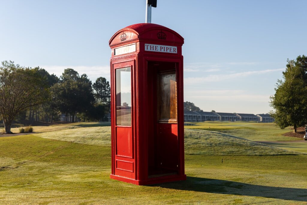 The red British telephone box on the first tee of The Piper, with the Legends villas across the course behind it