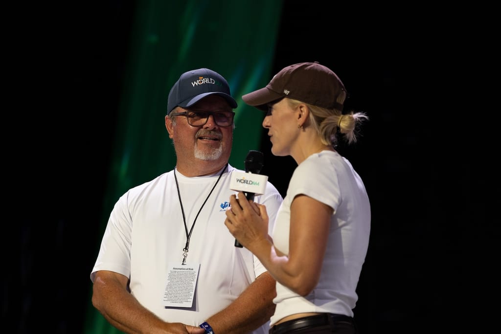 A World Am official being interviewed on stage with a branded microphone