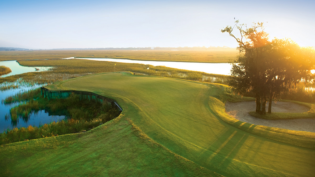 The 13th green at Pawleys Plantation at sunrise, with the bulkhead wall dropping into marsh water and tidal creeks stretching to the horizon
